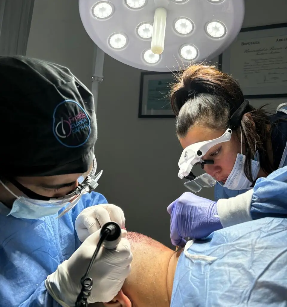 Dos médicos realizando una cirugía capilar en paciente, empleando técnicas avanzadas para tratar la caida de cabello.